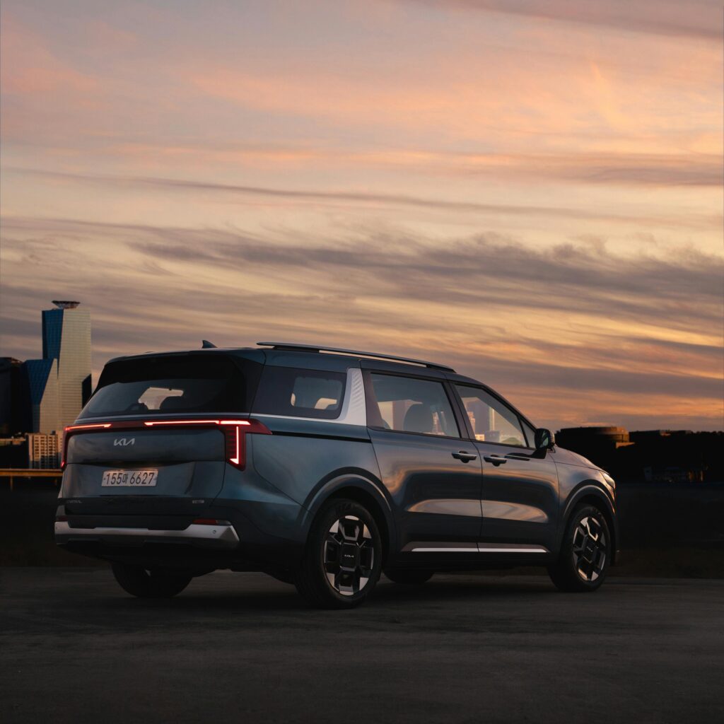 Black Kia Carnival on Parking Lot under Evening Sky